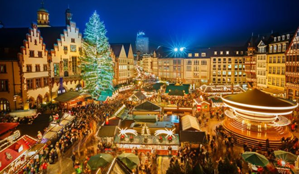 Vianočné trhy v Rakúsku sú plné ľudí obdivujúcich stánky a obrovský rozsvietený vianočný strom v historickom centre mesta.