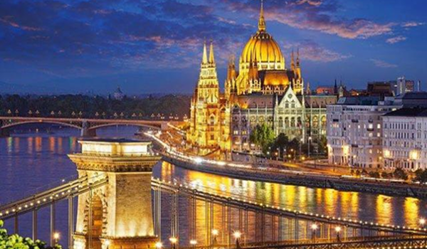 Krásne adventné trhy v Budapešti sú spojené s pohľadom na osvetlenú budovu Parlamentu a Reťazový most cez Dunaj v noci.