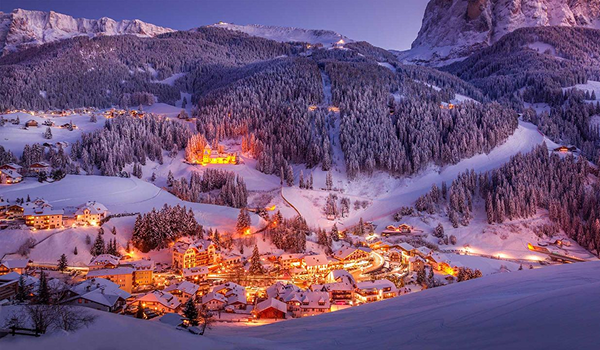 Osvetlená horská dedina v zime pri západe slnka, ideálna pre zimnú dovolenku.