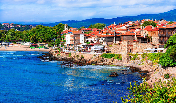Pohľad na historické mestečko Sozopol s typickými domami postavenými na skalnatom útese nad morskými vlnami.
