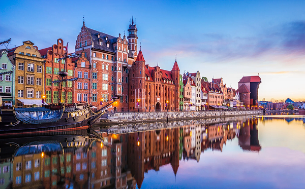 Historické nábrežie mesta Gdansk so stredovekým žeriavom Żuraw pri západe slnka