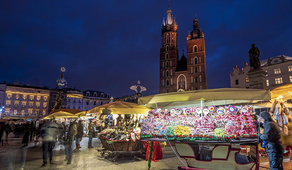 Krakovské vianočné trhy sa konajú na Hlavnom námestí s mnohými stánkami a vysokou vežou Mariánskeho kostola v pozadí.