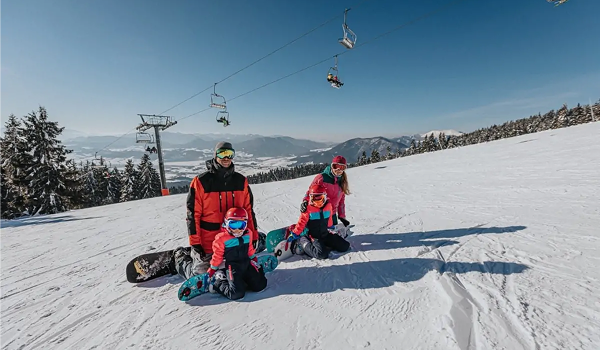 Šťastná rodina si užíva jarné prázdniny na lyžiach a snowboardoch v slnečnom horskom stredisku