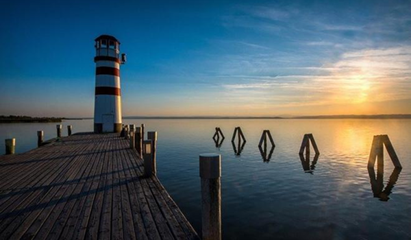 Malebný západ slnka nad Neziderským jazerom s majákom v Podersdorfe na konci dreveného móla.