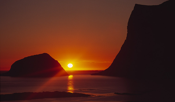 Nekonečný deň za polárnym kruhom: Zlatisté polnočné slnko osvetľujúce pokojnú hladinu mora