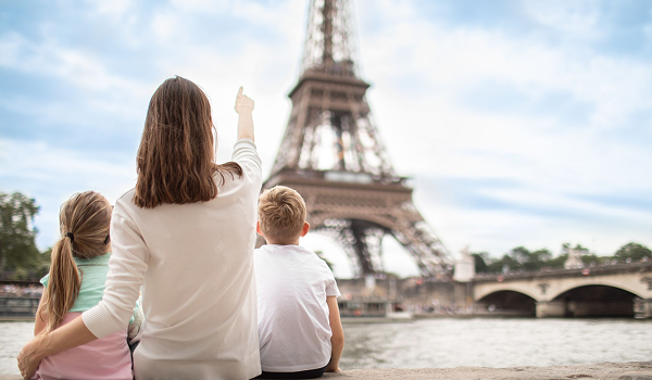 Matka s dvomi deťmi hľadí na Eiffelovu vežu počas rodinného poznávacieho zájazdu v Paríži.
