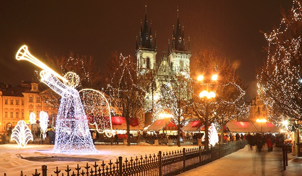 Oslava Silvestra v Prahe na Staromestskom námestí je zobrazená s vianočnými trhmi a veľkým osvetleným anjelom pred Týnskym chrámom.