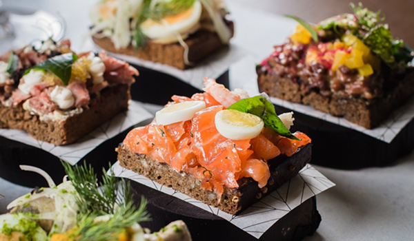 Detailný pohľad na štyri rôzne, bohato obložené dánske otvorené sendviče Smørrebrød (s lososom, roastbeefom, vajíčkom a inými prísadami).