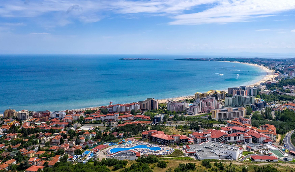 Panoramatický záber na prímorské letovisko Sveti Vlas s hotelovými komplexmi, bazénmi a dlhou piesočnatou plážou tiahnucou sa pozdĺž modrého mora.