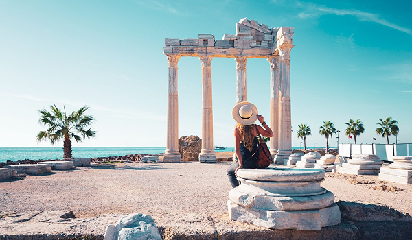 Turistka v klobúku obdivuje antické stĺpy Apolónovho chrámu v Side počas dovolenky v Turecku.
