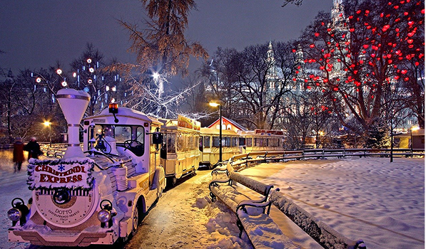 Vianočné trhy vo Viedni na Maria-Theresien-Platz ponúkajú jazdu vianočným vláčikom Christkindl Express uprostred zasneženého parku.