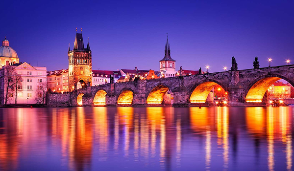 Romantický pohľad na Karlov most a Vltavu osvetlený v noci.